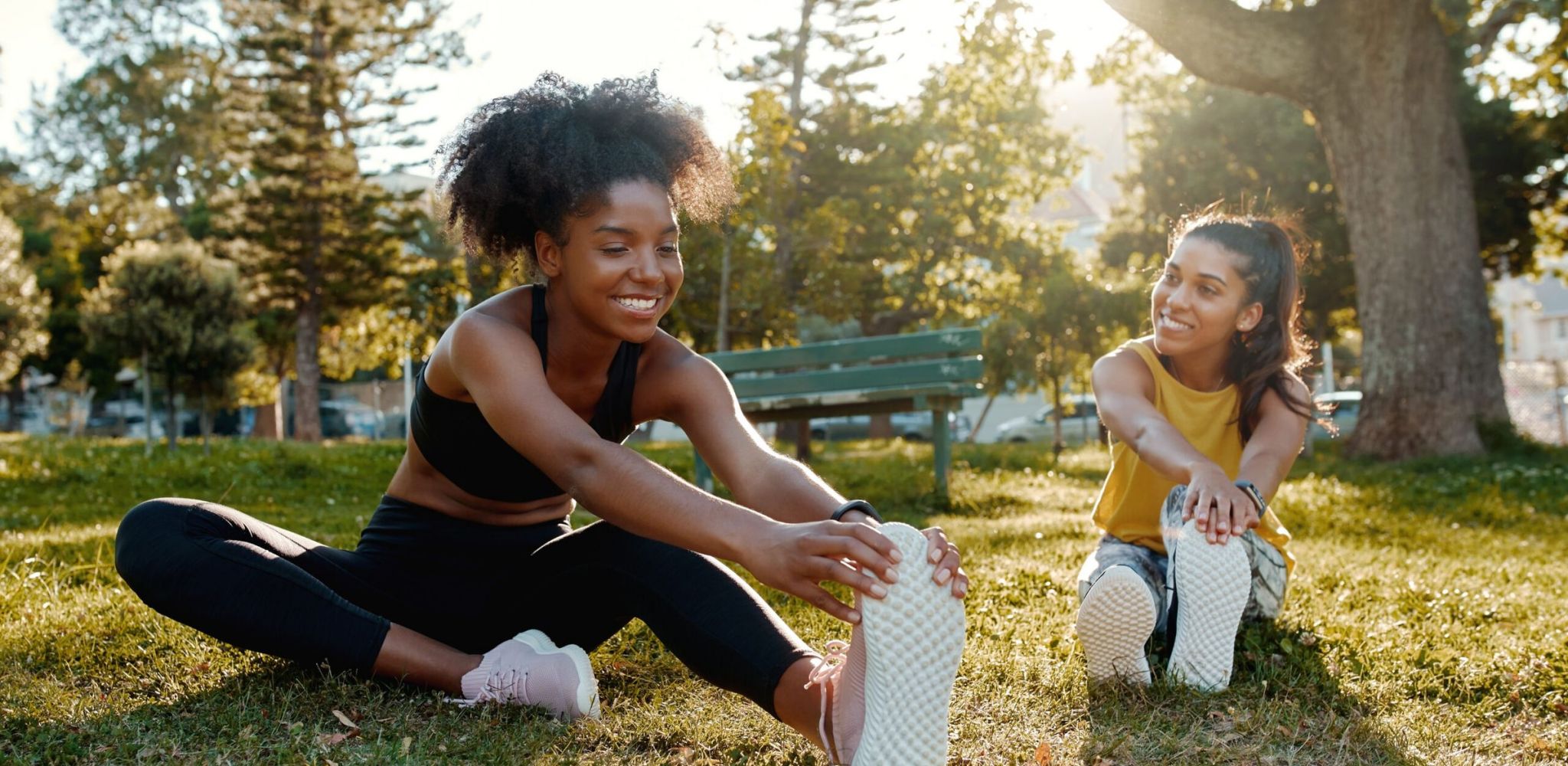 Encore at Reems Creek female diverse friends doing stretching exercise in the park - diverse friends warming up before doing group exercise